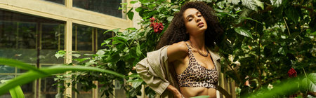 curly african american woman posing with hand on hip in her trendy look in exotic setting, banner