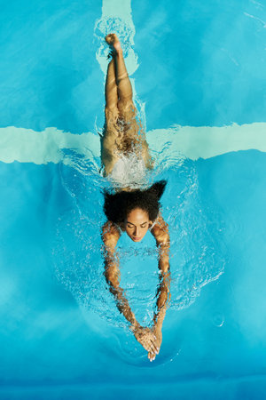 top view of young african american woman swimming in clear pool water, serene and peacefulの写真素材