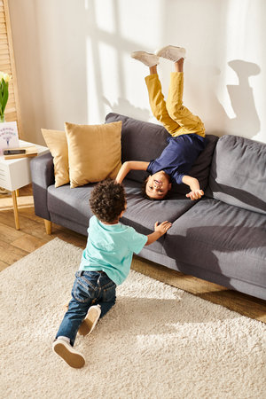 joyous african american mother sitting on sofa with her adorable sons in living room at homeの写真素材