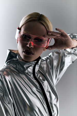peculiar woman with sci fi glasses in futuristic attire doing robotic motions and looking at cameraの写真素材