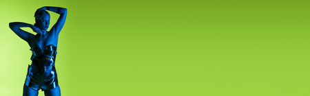 peculiar beautiful woman in futuristic sci fi attire posing in blue lights on green backdrop, bannerの写真素材