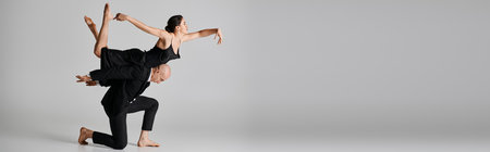 Graceful dance, young couple performing an acrobatic routine in studio setting on grey, banner