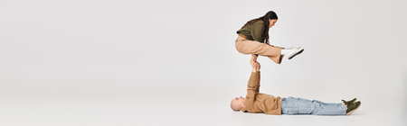 performance of artistic couple banner, woman in casual clothes balancing on hands of man on grey