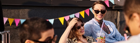 jolly young friends with trendy sunglasses sitting on roof and drinking cocktails at party, banner