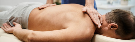 cropped view of dedicated doctor massaging his mature patient during rehabilitation, banner
