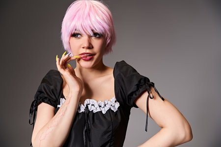 appealing woman cosplaying sexy anime character with pink hair and looking away on gray background