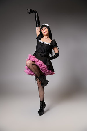 attractive sexy female cosplayer in tempting maid costume looking at camera on gray backgroundの写真素材