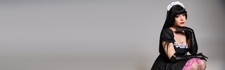 sexy female cosplayer in tempting maid costume looking at camera on gray background, bannerの写真素材