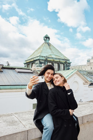 happy lgbt couple taking selfie on smartphone while standing together on street in Vienna, lesbianの写真素材