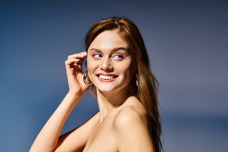 Side view beauty shot of cheerful woman smiling, touching her hair on dark blue backgroundの写真素材