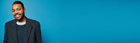banner of african american young guy in dark blue outfit smiling to camera on vibrant backgroundの写真素材