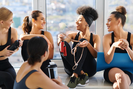 group of happy and young interracial women in active wear chatting after workout in pilates studioの写真素材