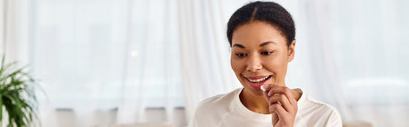 banner of happy african american woman taking pill at home, perfect for health and wellness