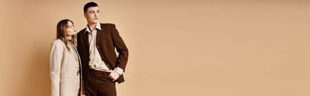 loving appealing couple in stylish suits posing together and looking away on pastel backdrop, bannerの写真素材