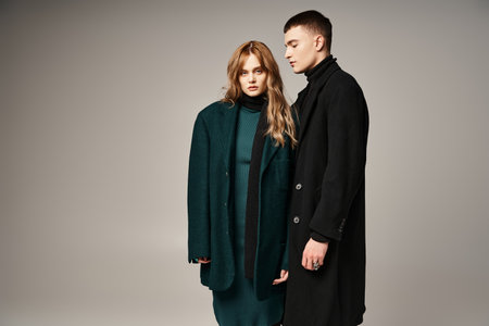 good looking man in coat posing lovingly next to his beautiful girlfriend who looking at camera