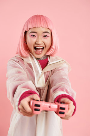 lovely asian woman in 20s in stylish outfit happy playing to joystick against vibrant background