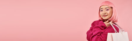 horizontal view of attractive asian woman in 20s posing with packets against pink backgroundの写真素材