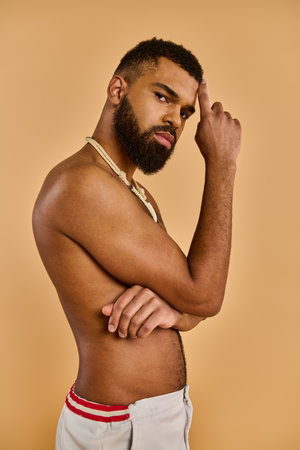 A man with a long, bushy beard stands with a confident stance, shirtless, showcasing his rugged and free-spirited essence.の写真素材