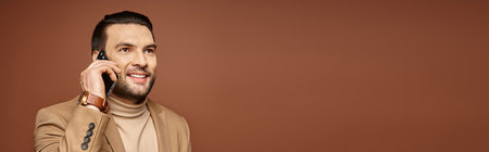 banner of handsome man with bristle smiling and having phone call on smartphone, beige backdrop