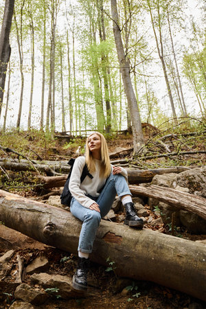 Active healthy woman hiking in beautiful forest, young blonde female hiker resting during trekkingの写真素材