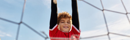 A playful young boy hangs upside down in a colorful volleyball net, showcasing his adventurous spirit and love for unique activities.の写真素材