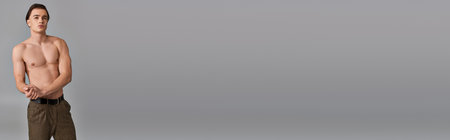 sexy shirtless man in brown pants posing attractively on gray backdrop and looking away, bannerの写真素材