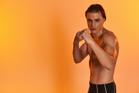 appealing young muscular man in shorts posing topless and boxing actively and looking at cameraの写真素材