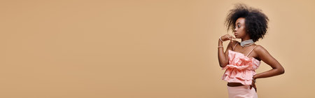 pretty african american woman posing in peach ruffle top and pastel skirt with hand on hip, bannerの写真素材