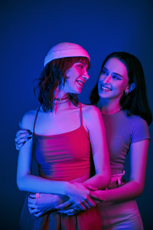 tender moment under purple lights of cheerful lesbian couple with bold makeup, generation z loveの写真素材