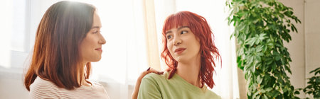 happy lgbt couple sharing tender moment on cozy sofa, banner of lesbian women looking at each otherの写真素材