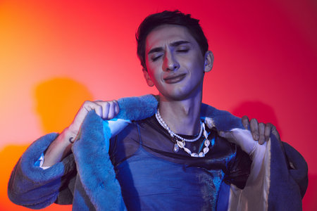 fancy alluring androgynous man in purple faux fur posing with closed eyes on vibrant backdrop