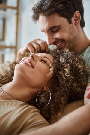 Closeup of curly young woman lying with her boyfriend smiling and laughing togetherの写真素材