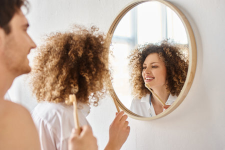 Morning couple in love in bathroom. Young happy couple smiling while brushing teeth in bathroomの写真素材