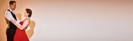 Side view of mature attractive smiling couple dancing ballroom dance on grey background, bannerの写真素材