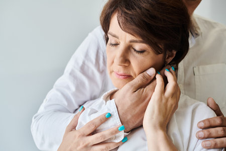 Closeup portrait of attractive middle aged wife hugging male hand touching her face, husbandの写真素材