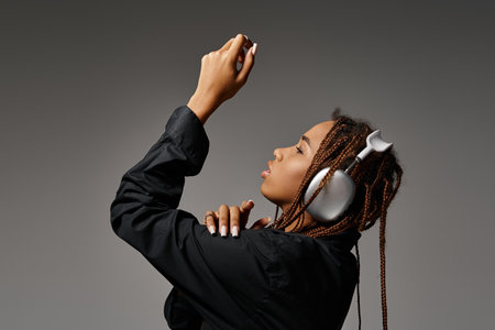 african american woman with dreadlocks listening music in headphones and looking away on greyの写真素材
