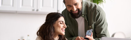 appealing loving couple of bearded man and disabled woman looking at phone in kitchen, banner