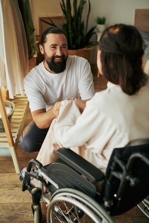 good looking cheerful man spending time with his beautiful disabled wife while in bedroom at home