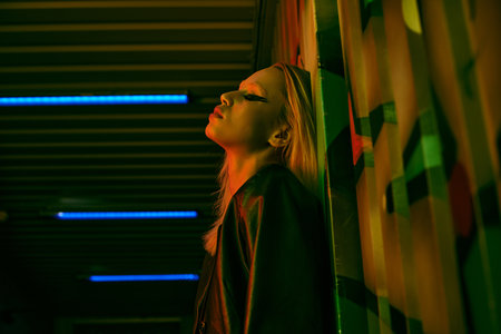Woman leaning against wall, eyes closed