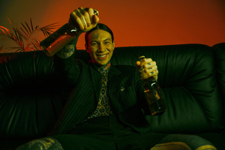 A man sitting on a couch holding a bottle of beer