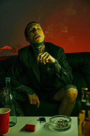 A man sits on a couch in a dimly lit room