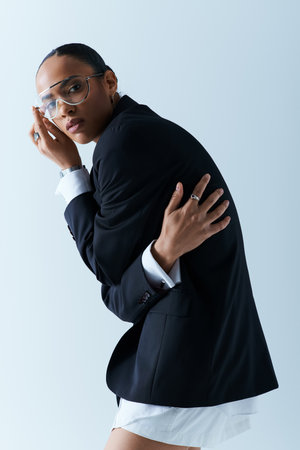 A stylish black woman in a suit and tie confidently posing in a studio setting.の写真素材