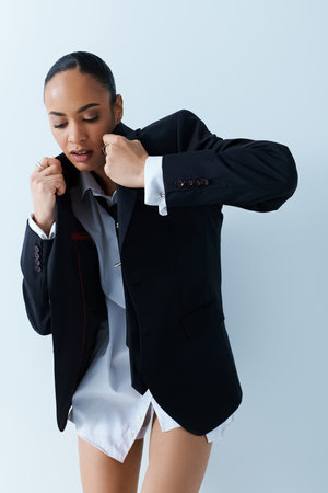 Young African American woman in black jacket and white shirt exudes confidence in studio setting.の写真素材