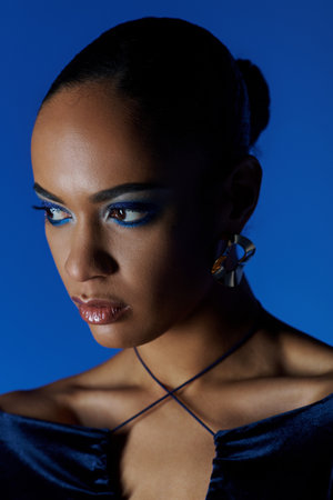 A young African American woman stands in a black dress, her piercing blue eyes captivating the viewer.の写真素材