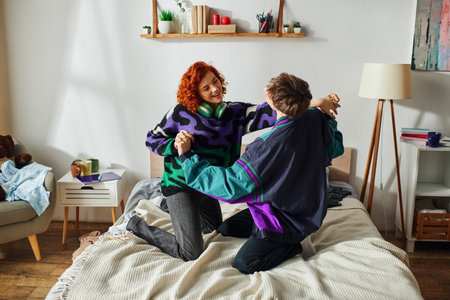 appealing cheerful boyfriend and girlfriend in vivid attires having much fun on bed at home