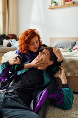 beautiful red haired woman in vibrant outfit hugging her loving joyous boyfriend while at home