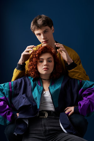 fashionable good looking couple in vivid stylish clothes hugging lovingly and looking at camera