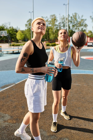 Two young women standing confidently on a basketball court, exuding strength and determination in...