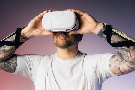 A man in a white shirt holds a white object over his head, immersed in a virtual reality headset in...