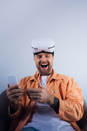 Man sitting in chair, immersed in phone screen, surrounded by virtual reality technology in a studio...